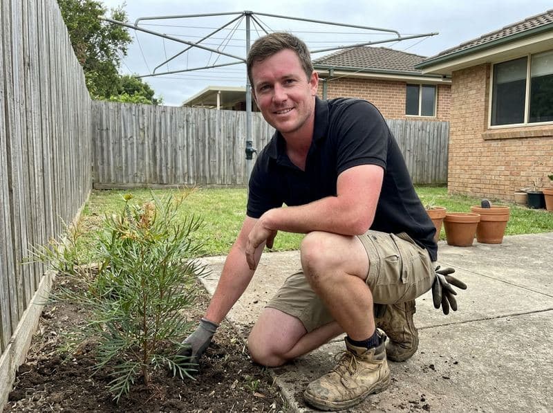 Scott crouching beside a native garden bed in a Northern Beaches residential garden
