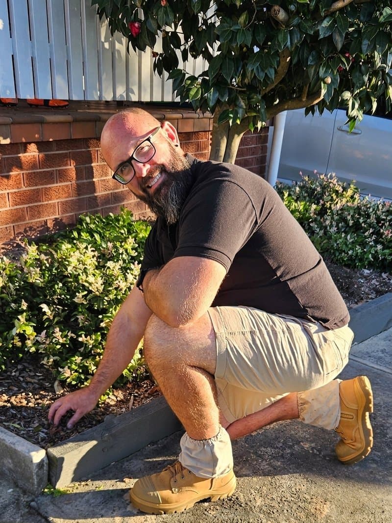 Scott working on a garden edge beside a trimmed hedge